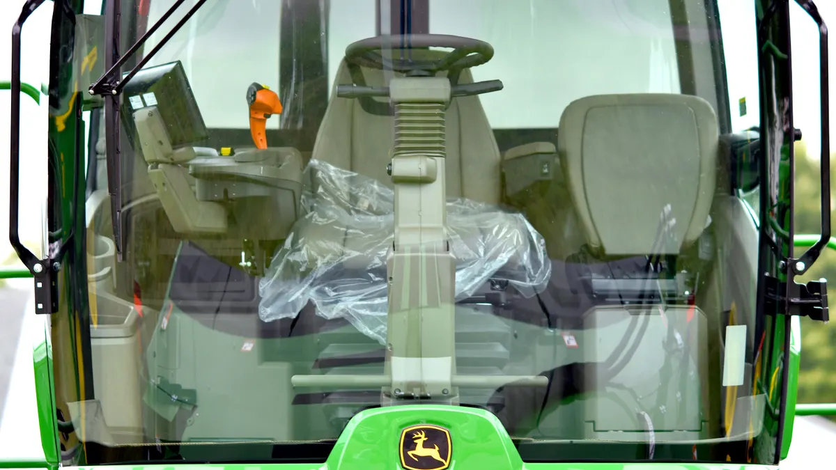 tractor cab with seat and controls behind windshield